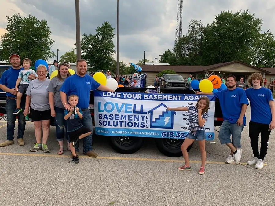 Lovell Basement Solutions, LLC family and company employees posing in front of business sign - Edwardsville, IL