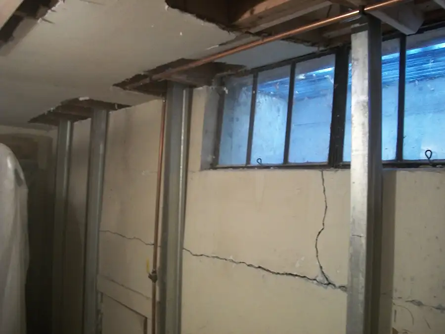 bowing basement wall with window, repaired with steel beam supports holding the wall up and in place - Belleville, IL